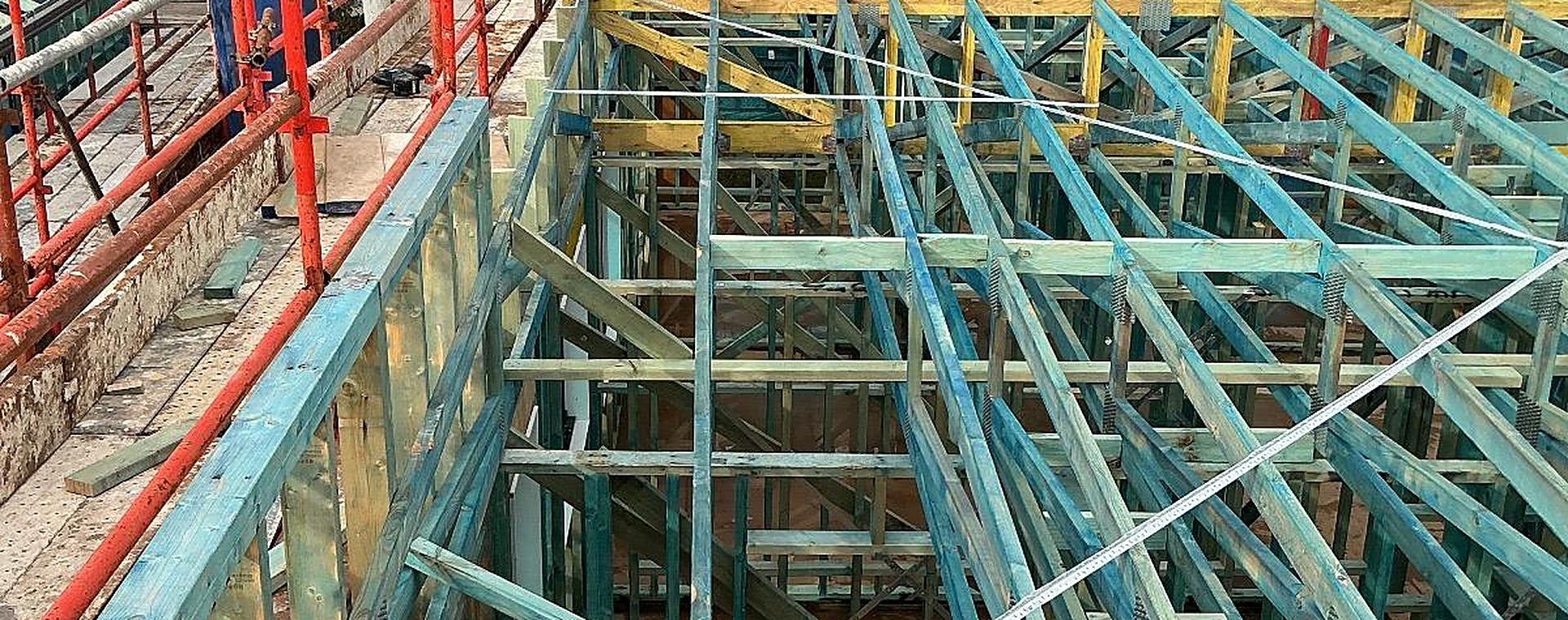 Upper-storey wall frames and ceiling framing seen from the scaffold